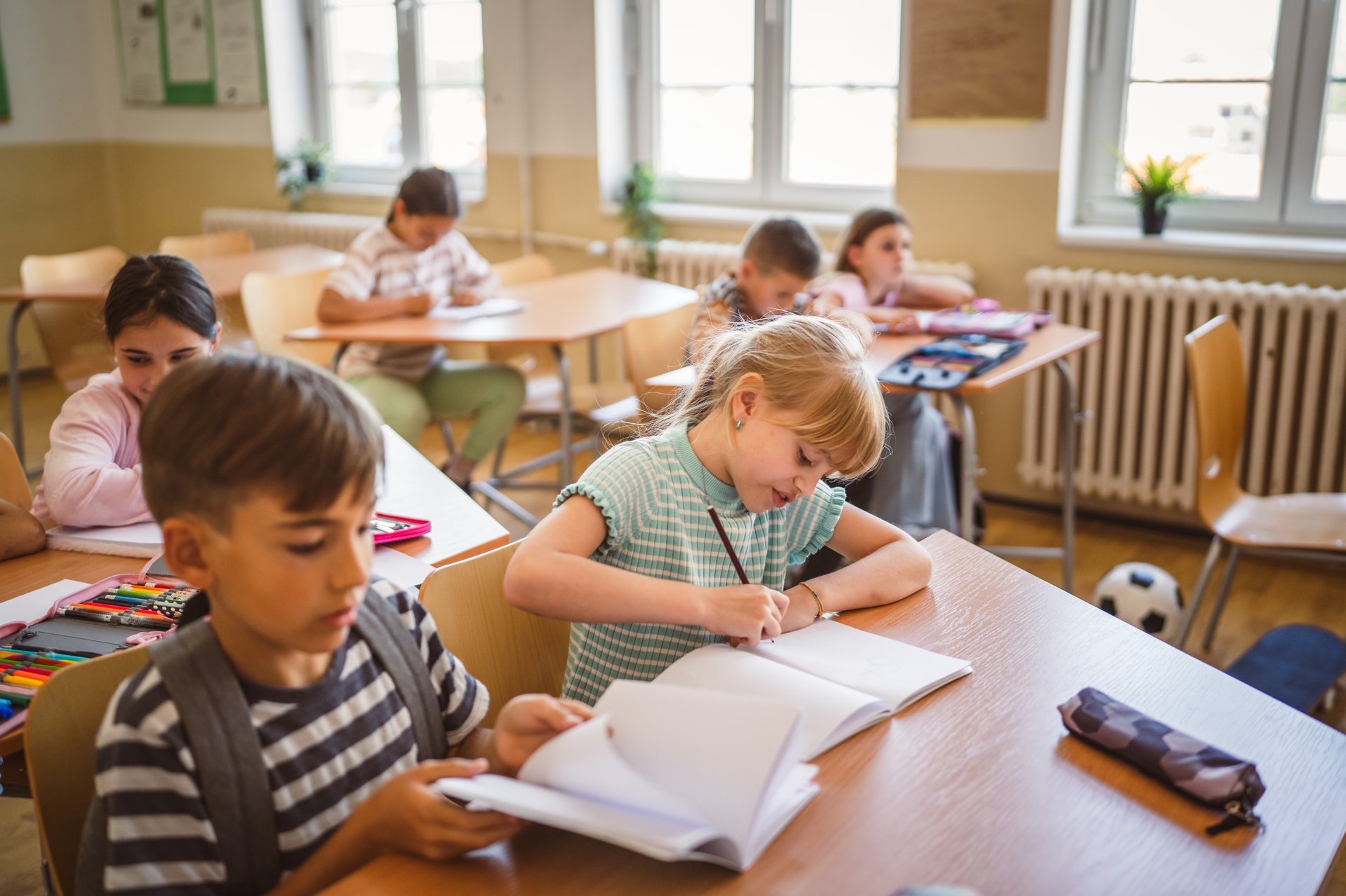 Estudiantes de primaria aprendiendo con entusiasmo en el aula con materiales escolares coloridos y decoraciones divertidas